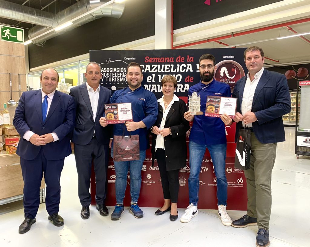 Recogen el premio los dos cocineros del Bar Ulzama y le acompañan los representantes de las empresas que les entregan premios. Recibe diploma, Fachada en plata del Ayuntamiento de Pamplona otorgada por el Ayuntamiento de Pamplona, pack de 1 noche de hotel, spa y desayuno para dos personas cortesía del Hotel Castillo de Gorraiz & Spa y una caja de vino de Cooperativa de Liédena.