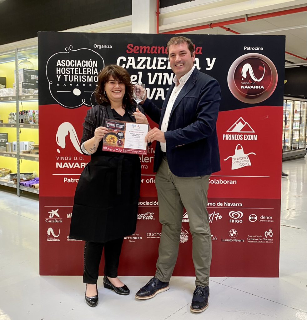 Recoge el premio Natalia Ecay, propietaria de la Antigua Farmacia y el Presidente de la Denominación de origen Vinos Navarra, le entrega diploma y premio que consiste en obsequiar al ganador tantas copas de vino, como kilos tenga en su haber y un delantal de Vinos D.O. Navarra.