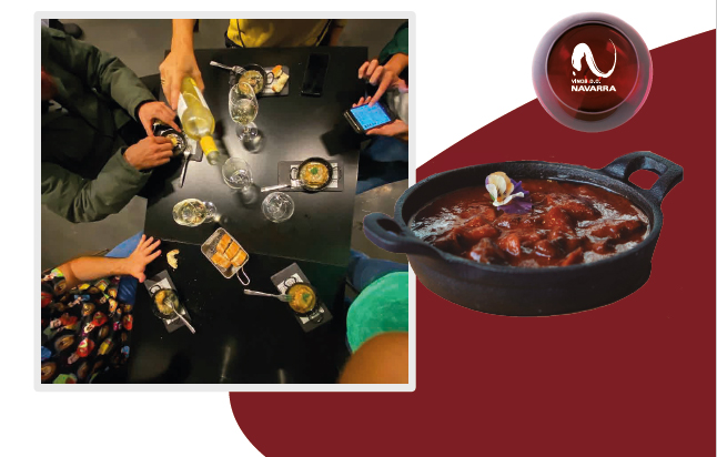Personas diversas alrededor de una mesa disfrutando de unas cazuelicas maridadas con vino D.O. Navarra